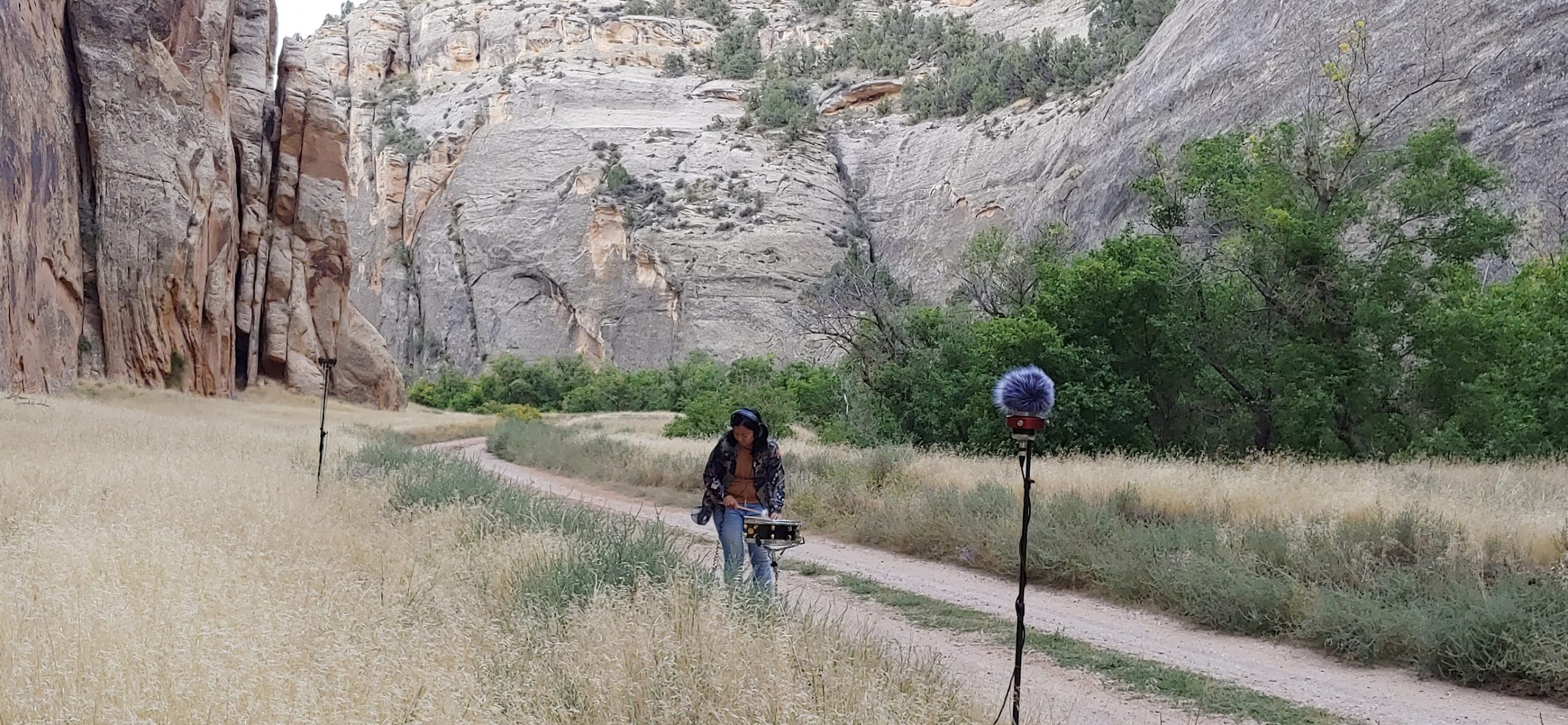 Pilipinx woman percussionist recording a snare in the echos of a canyon at Dinosaur Monument Park in Colorado and Utah border.
